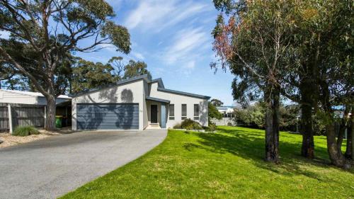 a white house with a driveway at Pelican House - Modern Family Retreat in Lakes Entrance