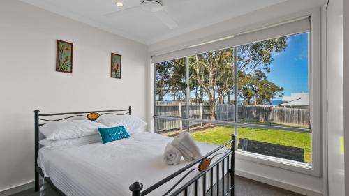a bedroom with a bed and a large window at Pelican House in Lakes Entrance