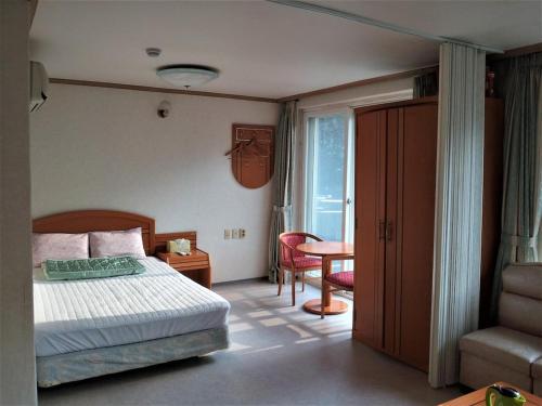 - une chambre avec un lit, une chaise et une table dans l'établissement Galcheon Family Resort, à Yangyang