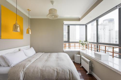 a bedroom with a large bed and large windows at Xujiahui park 2BR Apt in Shanghai