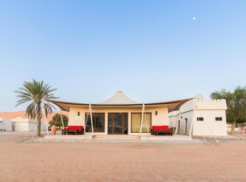 a building with red chairs and a palm tree at Desert Nights Resort in Shāhiq