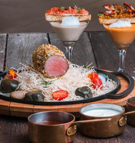 a plate of food with pasta and meats and two drinks at Desert Nights Resort in Shāhiq
