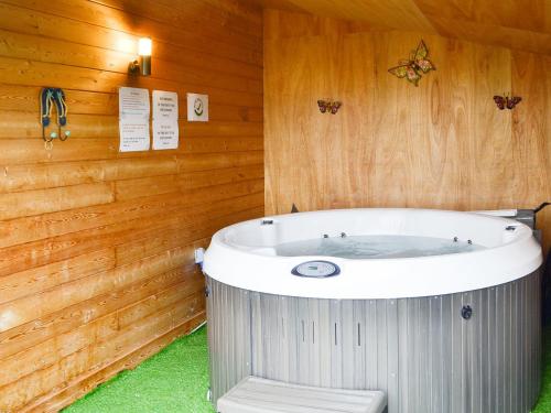 a bath tub in a room with a wooden wall at Ty Nant - Uk32239 in Lower Chapel
