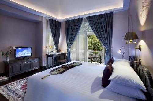 a bedroom with a large bed and a television at Ping Nakara Boutique Hotel And Spa in Chiang Mai