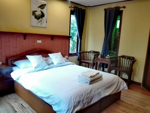 1 Schlafzimmer mit einem großen weißen Bett mit 2 Stühlen in der Unterkunft Luang Chumni Village in Phra Nakhon Si Ayutthaya