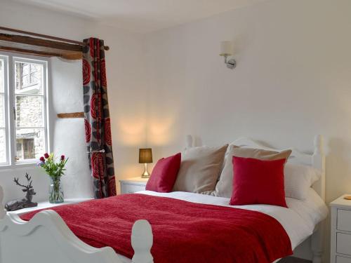 a white bed with red pillows and a red blanket at Moortown in Chulmleigh