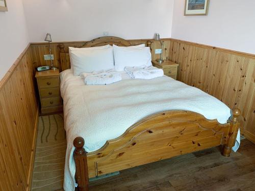 1 dormitorio con 1 cama de madera y 2 toallas en Teenys Cottage, en Flashader