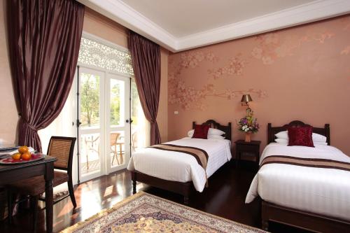 a hotel room with two beds and a window at Ping Nakara Boutique Hotel And Spa in Chiang Mai