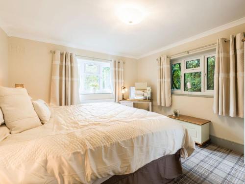 a bedroom with a large bed and two windows at Hampsfell Cottage - Uk1518 in Grange Over Sands