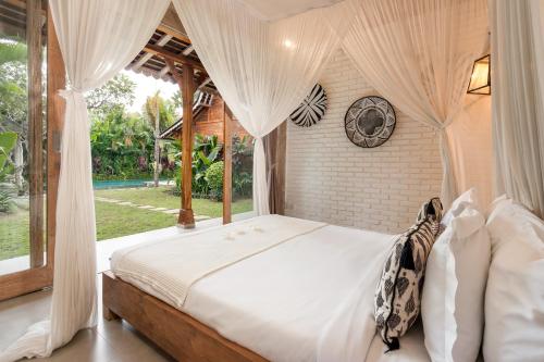 a bedroom with a canopy bed with a window at Villa Little Mannao in Kerobokan