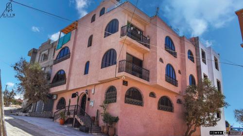 a large pink building with windows and stairs at Auberge RIAD DLIM Tamraght in Tamraght Ouzdar