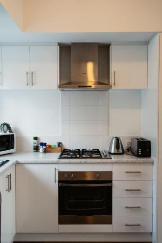a kitchen with white cabinets and a stove top oven at Premalaya in Yallingup