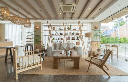 een woonkamer met een bank en een tafel en stoelen bij Tribe Pattaya SHA certificated in Jomtien Beach