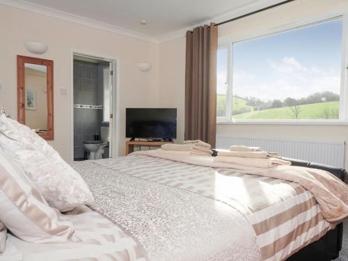 a bedroom with a large bed with a large window at Longmead in Berry Pomeroy