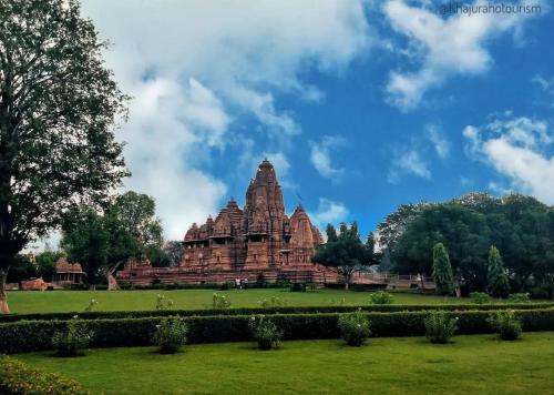 een tempel in een park met een groen veld bij Namaste Homestay in Khajurāho