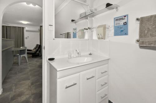a white bathroom with a sink and a mirror at Balgal Beach Units in Rollingstone