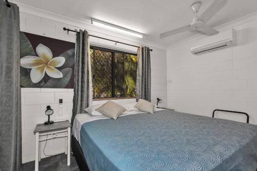 a bedroom with a blue bed and a window at Balgal Beach Units in Rollingstone