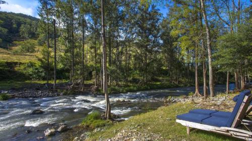 a blue chair sitting next to a river at Carawa River Retreat in Coneac