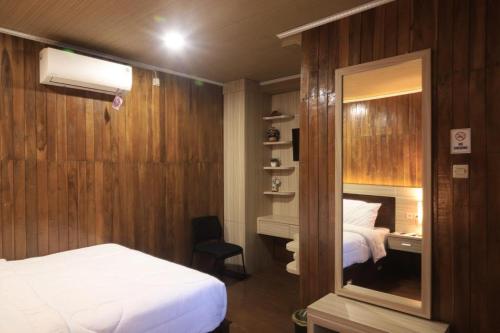 a bedroom with a bed and a desk with a mirror at d' Omah Afi 1 in Jarakan