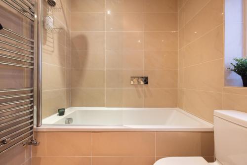 a bathroom with a tub and a toilet at NIRU Experience Huge Private Terrace In Chelsea in London