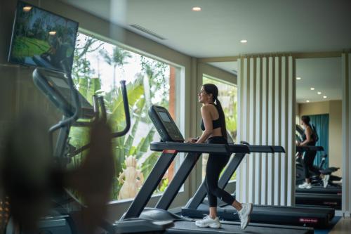 a woman running on a treadmill in a gym at Kappa Senses Ubud in Ubud
