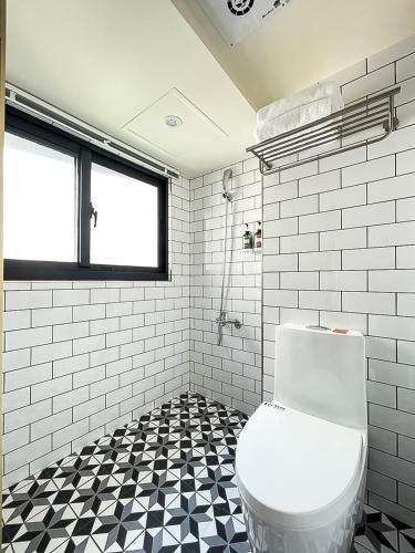 a bathroom with a toilet and a black and white tile floor at 旅行家 Affetto Hostel in Taichung