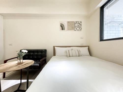 een slaapkamer met een bed, een tafel en een raam bij 旅行家 Affetto Hostel in Taichung