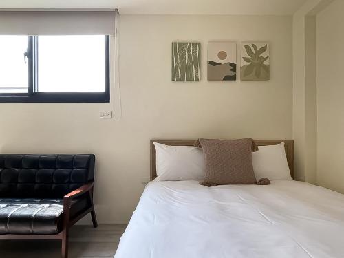 a bedroom with a bed and a black chair at 旅行家 Affetto Hostel in Taichung