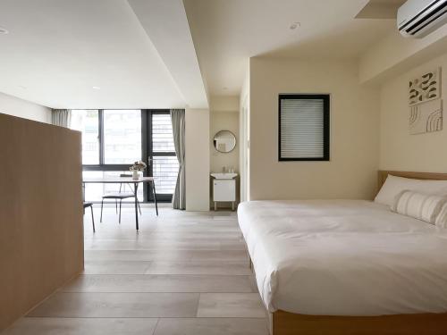 a bedroom with a bed and a dining room with a table at 旅行家 Affetto Hostel in Taichung