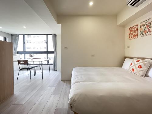 a bedroom with a bed and a dining room with a table at 旅行家 Affetto Hostel in Taichung
