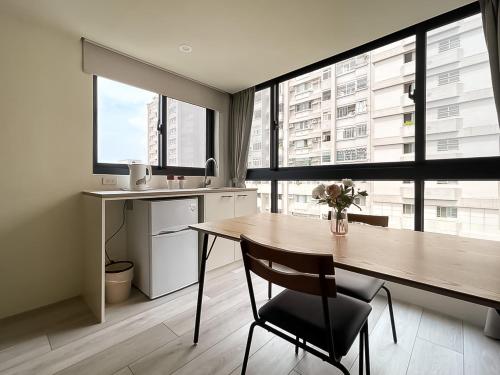 a kitchen with a wooden table with a chair and windows at 旅行家 Affetto Hostel in Taichung