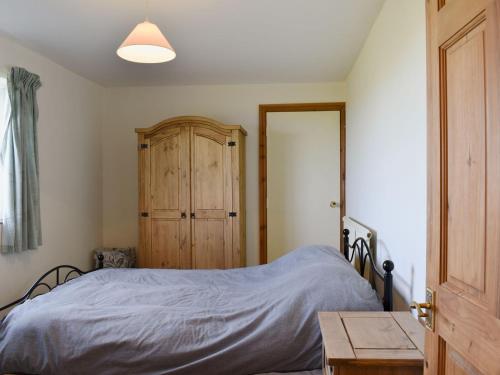 a bedroom with a bed and a wooden cabinet at Kings Cottage in Combe Martin