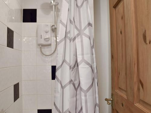 a shower in a bathroom with a white shower curtain at Kings Cottage in Combe Martin