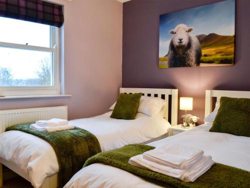 a room with two beds and a picture of a sheep at 10 Elm Court in Keswick