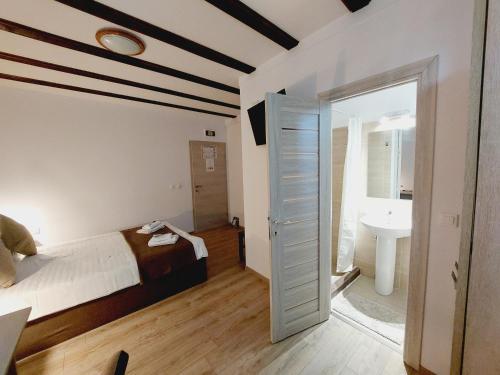 ein Schlafzimmer mit einem Bett und ein Badezimmer mit einem Waschbecken in der Unterkunft Confort INN in Otopeni
