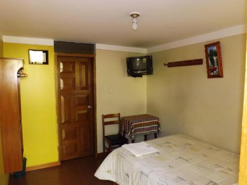1 dormitorio con 1 cama y TV en la pared en El Álamo, en Arequipa