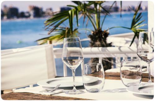 four wine glasses sitting on a table with a view of the ocean at Hotel Muva Beach in Peñíscola
