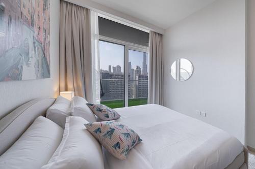 a white bedroom with a couch and a large window at Alluring 1 BD Apartment in Business Bay with Burj Khalifa view in Dubai