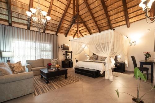 a bedroom with a canopy bed and a living room at Kruger Eden Lodge in Marloth Park