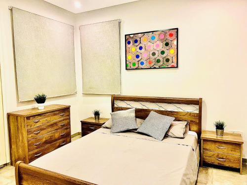 - une chambre avec un lit, deux commodes et un tableau dans l'établissement GRACE HOUSE, à Pýla