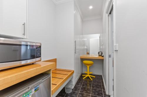 a small kitchen with a microwave and a stool at The International Motel Apollo Bay in Apollo Bay