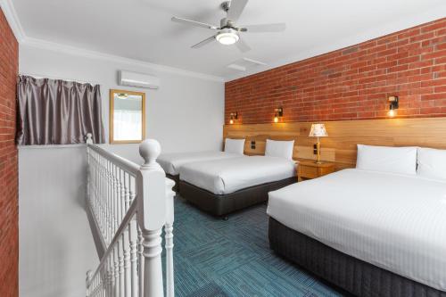 a hotel room with two beds and a brick wall at The International Motel Apollo Bay in Apollo Bay