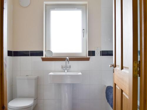 a bathroom with a toilet and a sink and a window at Taigh Iasg-uk30003 in Kingsburgh