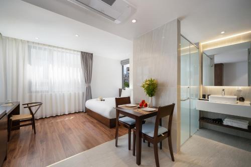 a hotel room with a bed and a table and a bathroom at Duke Casa Apartment in Da Nang
