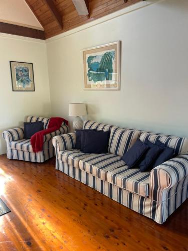 a living room with two couches and a wooden floor at Seafarer Cottage in South Mission Beach