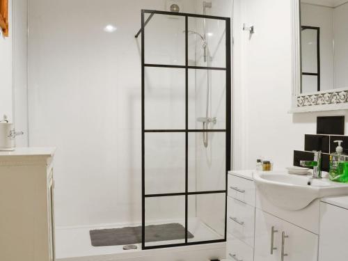 a white bathroom with a shower and a sink at 5 Church Square in Rigg