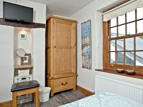 阿普多爾的住宿－Cobble Cottage，一间卧室设有木制橱柜和窗户。