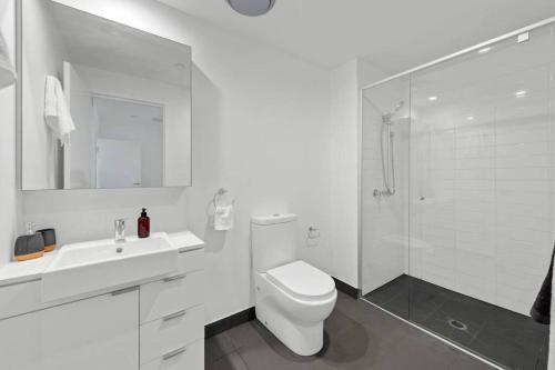 a white bathroom with a toilet and a shower at Lovely 2 Bedroom unit Pool,Gym workspace & more in Brisbane