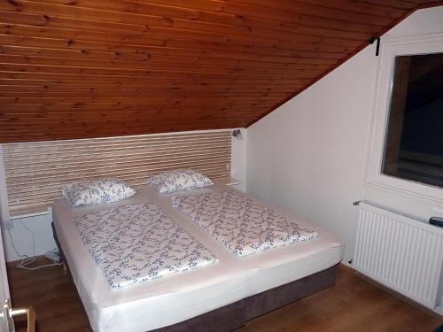 a bed in a room with a wooden ceiling at Levendula apartman in Kehidakustány