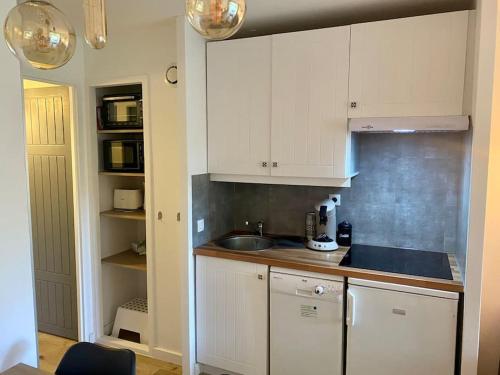 a kitchen with white cabinets and a sink at Appartement en résidence de vacances in Lacanau